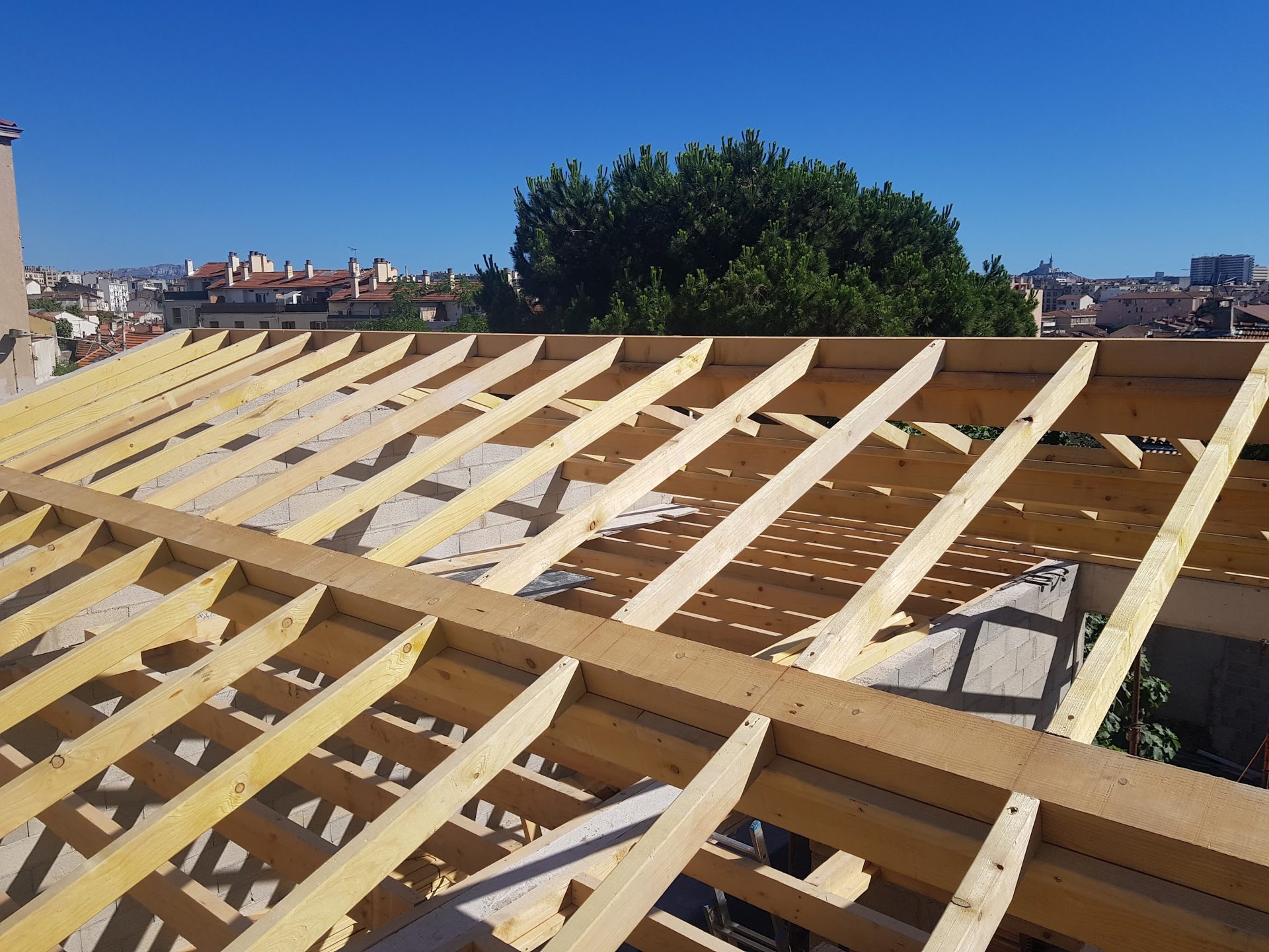 Solivage d'un toit-terrasse réalisé par MDB Charpente, avec vue sur Marseille et Notre-Dame de la Garde